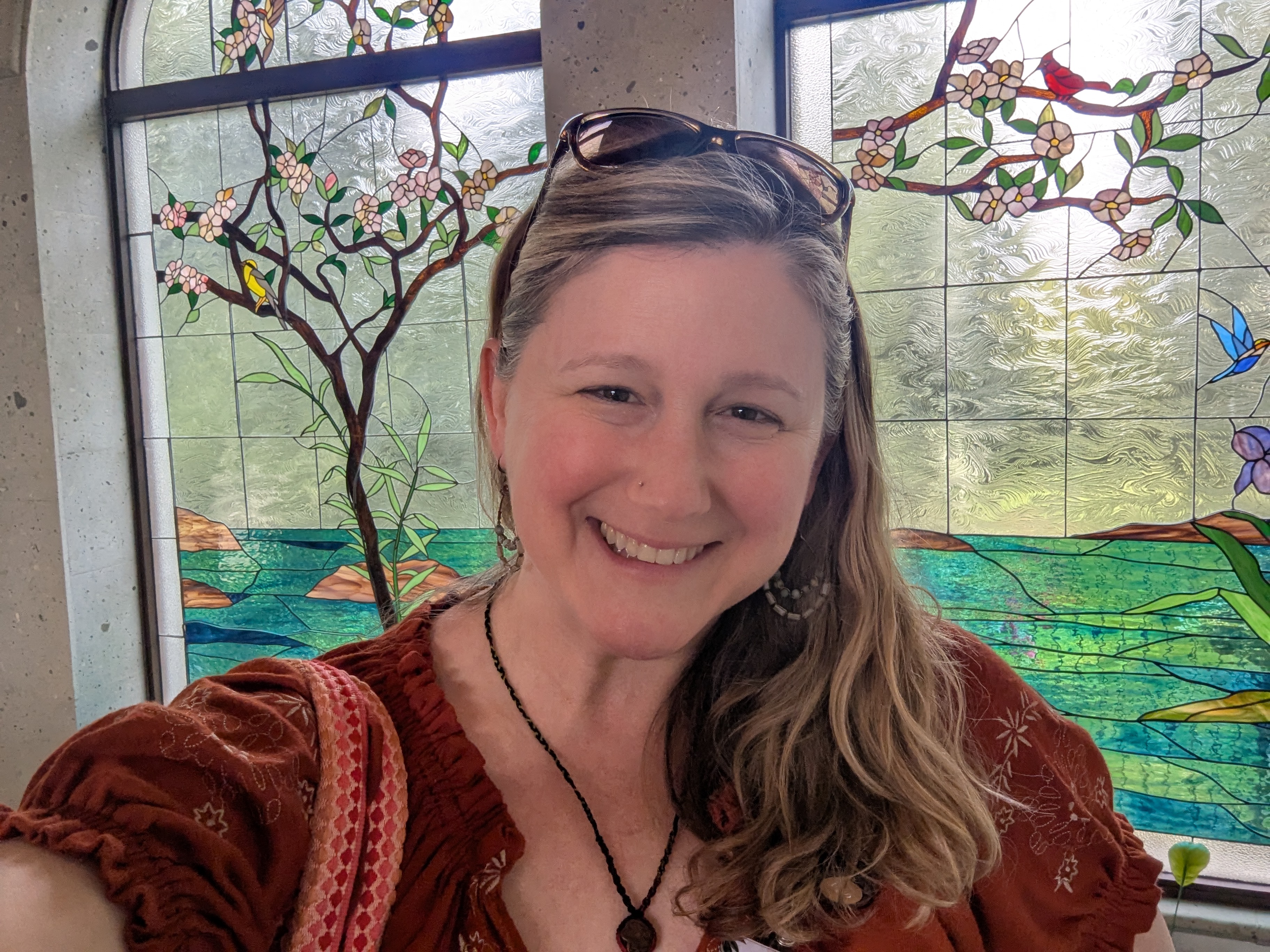 Robin Sherrell smiling in front of a stained-glass window